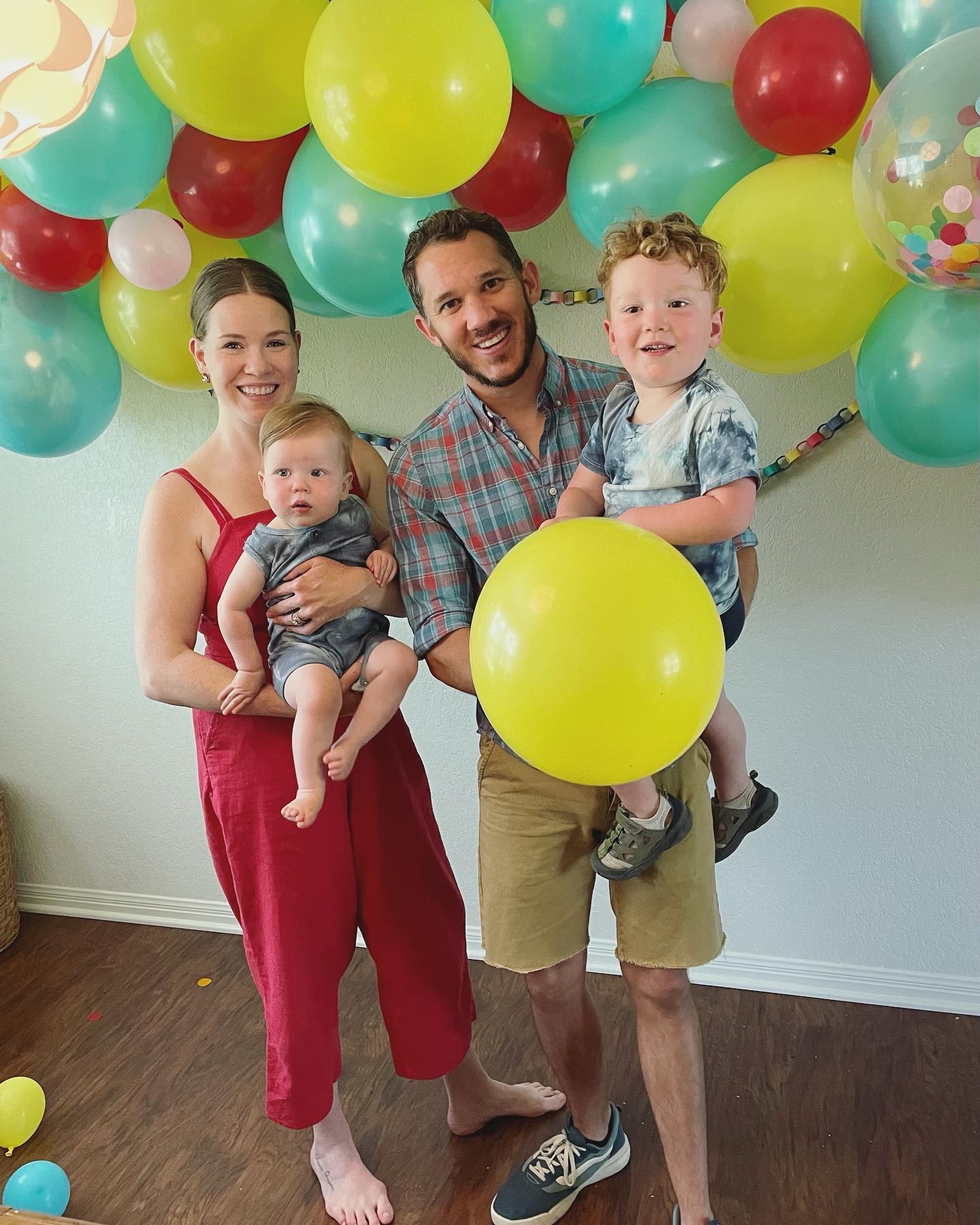 Family of four at a birthday celebration with balloons.